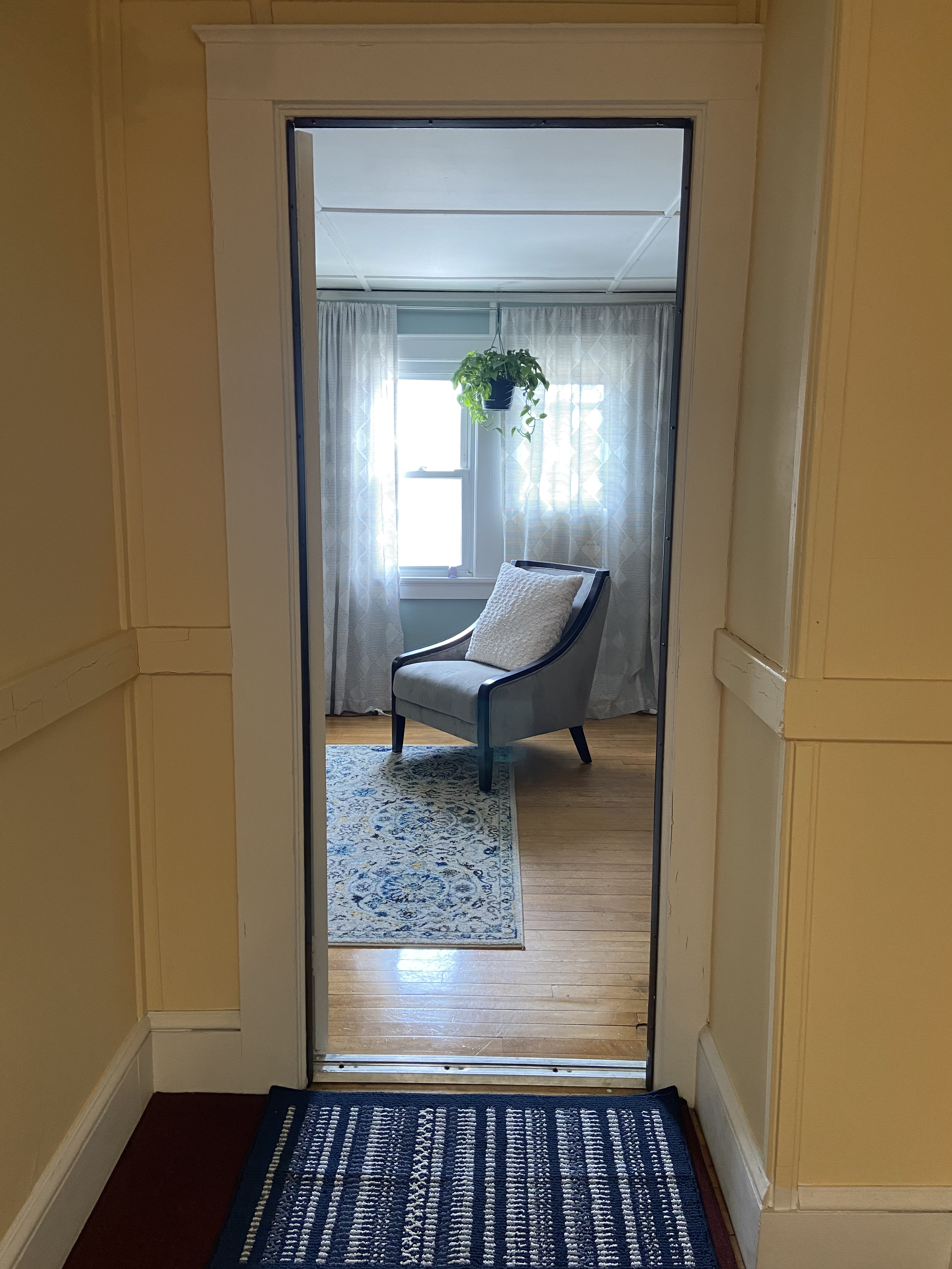 view of the therapy office room from a hallway, showing a single blue-gray couch on a blue rug.